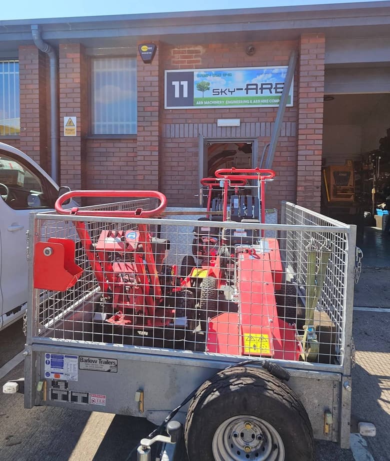 Unit 11, Dewar Court — the Sky-Arb workshop, with a caged trailer of stump grinders outside the roller door